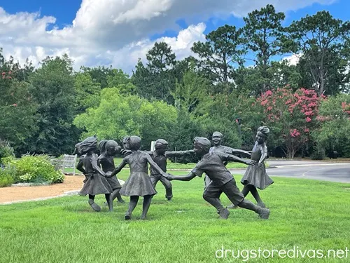 A statue of children playing ring around the rosy in a garden.
