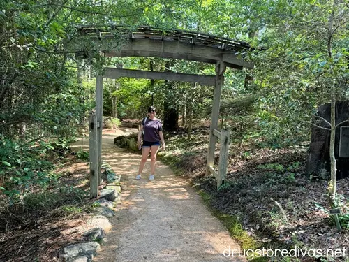 A woman standing under a wooden Japanese archway.