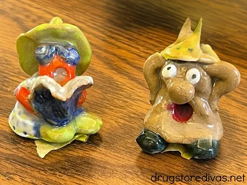 Two clay figurines on a wood desk.