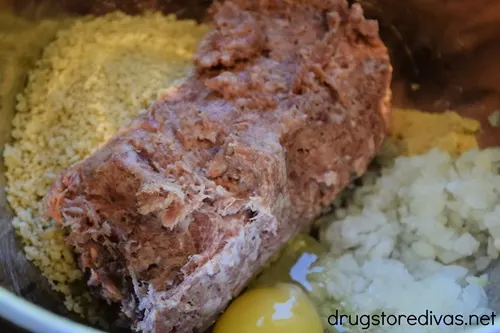 Panko bread crumbs, ground sausage, an egg, and chopped onions in a bowl.