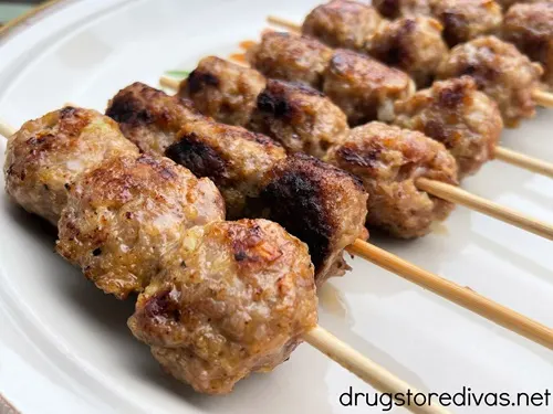 Grilled Ground Sausage Meatball skewers on a white plate.