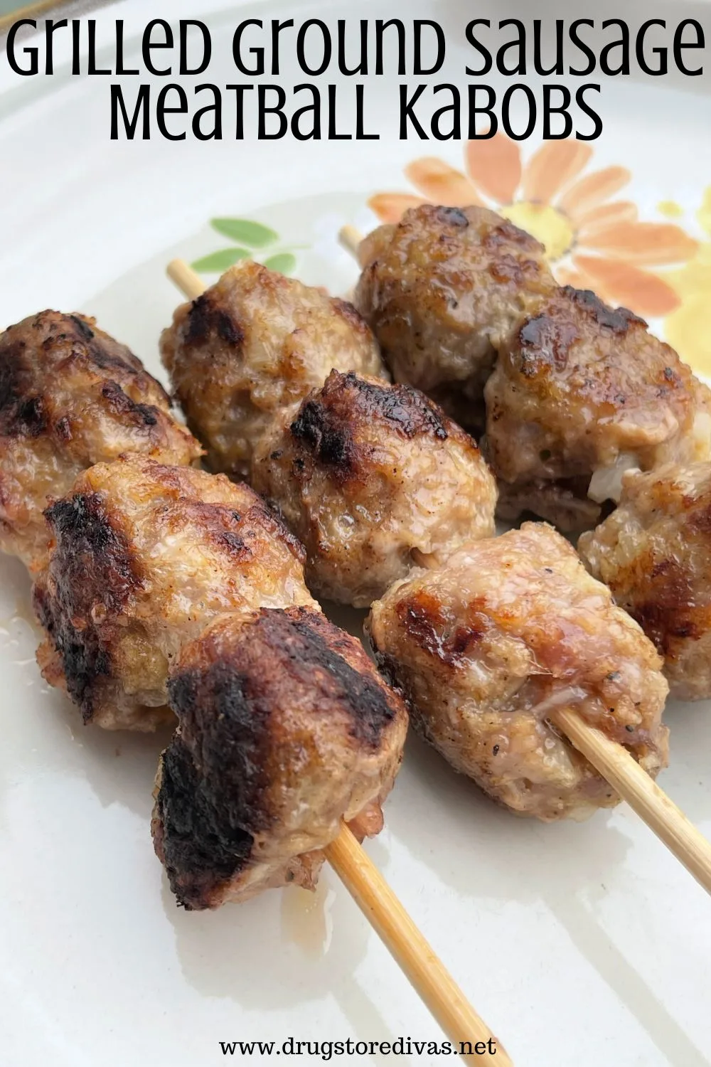 Three skewers with three meatballs each on a plate with painted flowers and the words 
