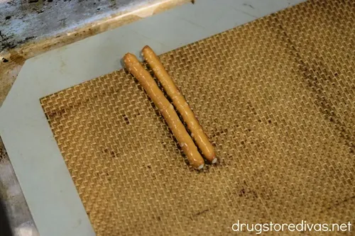 Two pretzel sticks on a silicone baking mat.