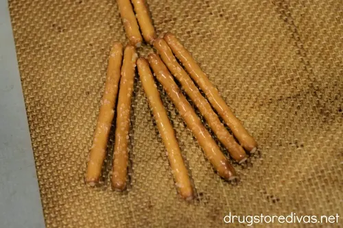 Six pretzel sticks fanned out on a silicone baking mat.