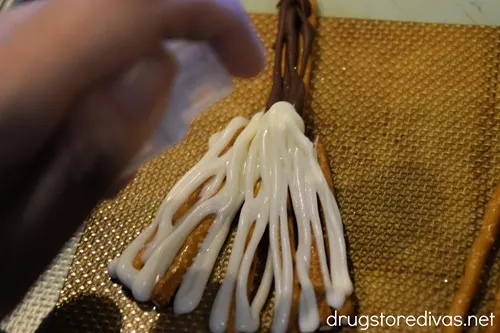 A hand spritzing something from a bottle onto a chocolate broom.