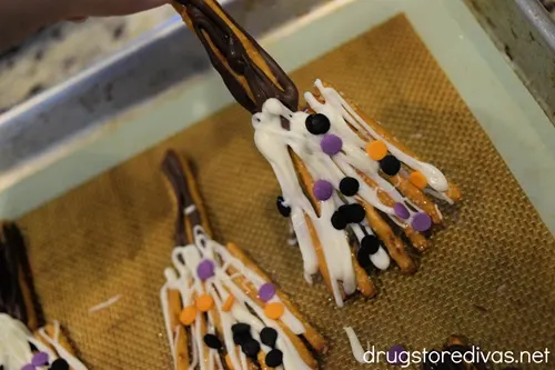Chocolate covered pretzel brooms on a sheet pan.