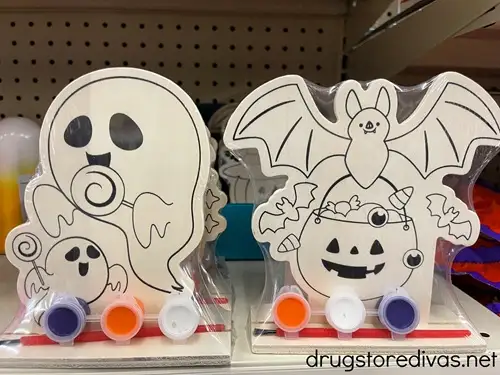 A ghost and a bat Halloween Wood Craft Kit with paint on a shelf in a store.