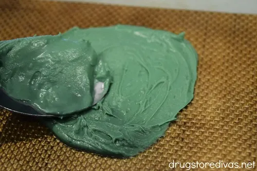 A circle of melted green chocolate bring spread with a spoon.