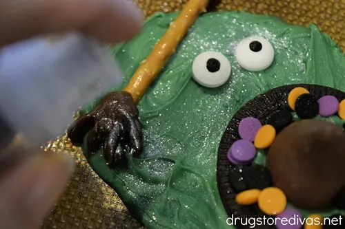 A finger spraying edible glitter on a melted witch candy.