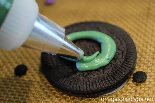 Green chocolate being piped onto an Oreo cookie.