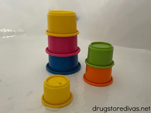 Colorful stacking cups in three piles in the bathtub.