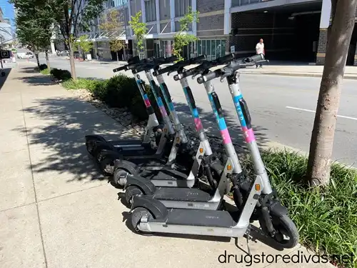 Six scooters, owned by the brand Bird scooter, lined up on a sidewalk in Nashville.