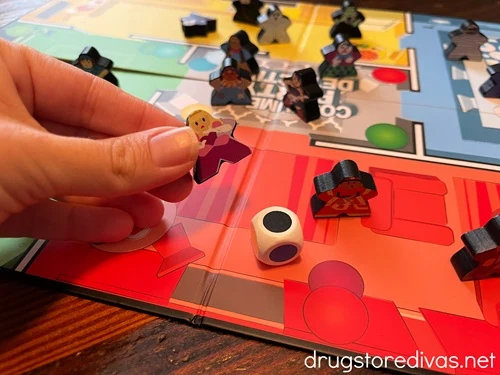 A board, characters, and a die for the board game Costume Party Detective.