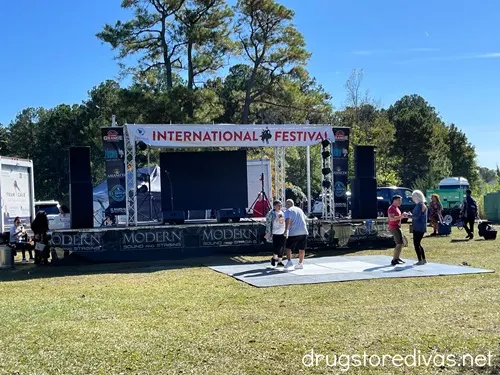 Two couples on a dance floor in front of a stage with a banner that says "International Festival" above them.