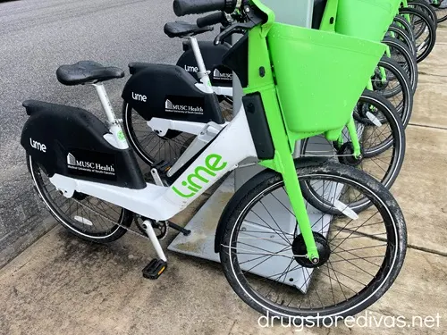 A few bikes with a green basket and a white body with the word LIME on it in a row.