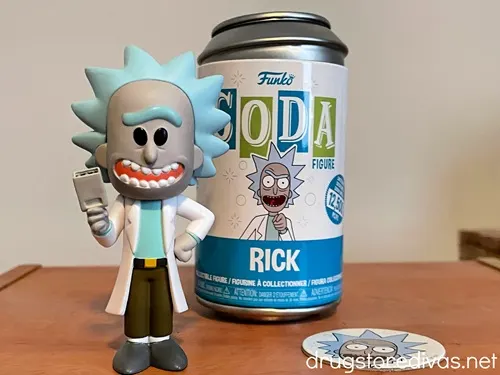 A soda can in the back with a Rick Sanchez from Rick and Morty figure in the front and a circle with Rick's face to the side on a table.