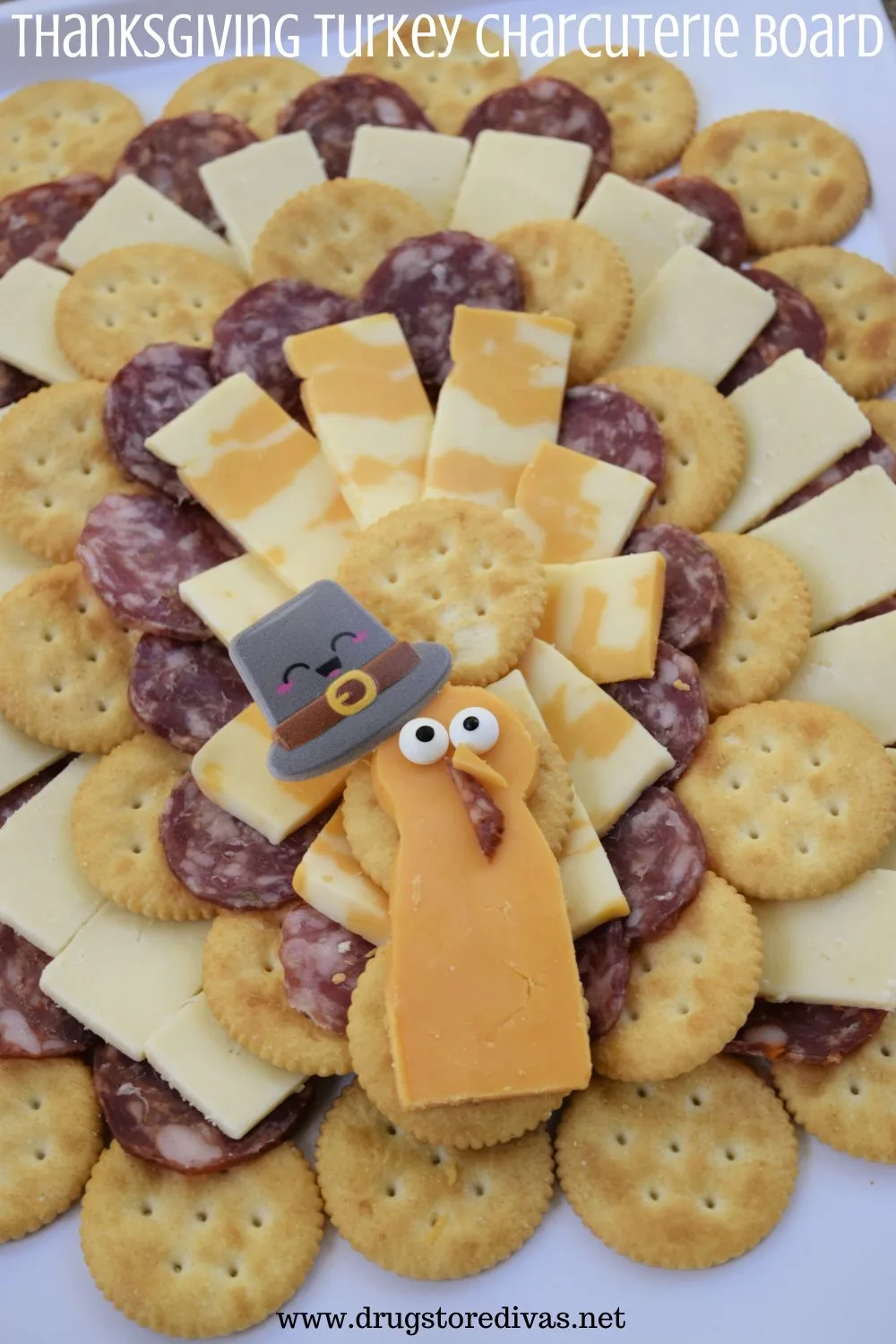 Meat, cheese, and Ritz crackers arranged on a white tray to look like a turkey with the words 