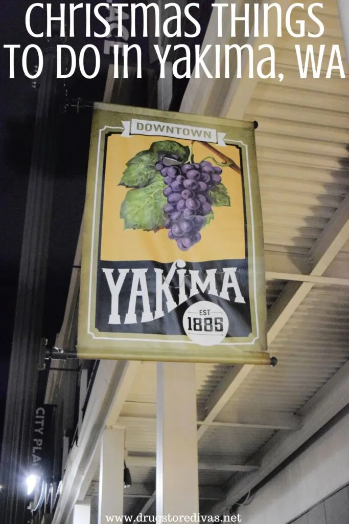 A sign with grapes and hops on it that says Yakima 1895 hanging off a building at night with the words "Christmas Things To Do In Yakima, WA" digitally written up top.