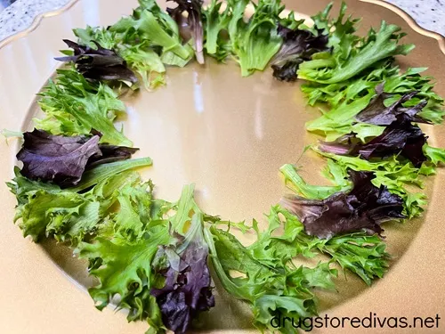 Green lettuce and purple cabbage arranged in a circle around a gold charger plate.