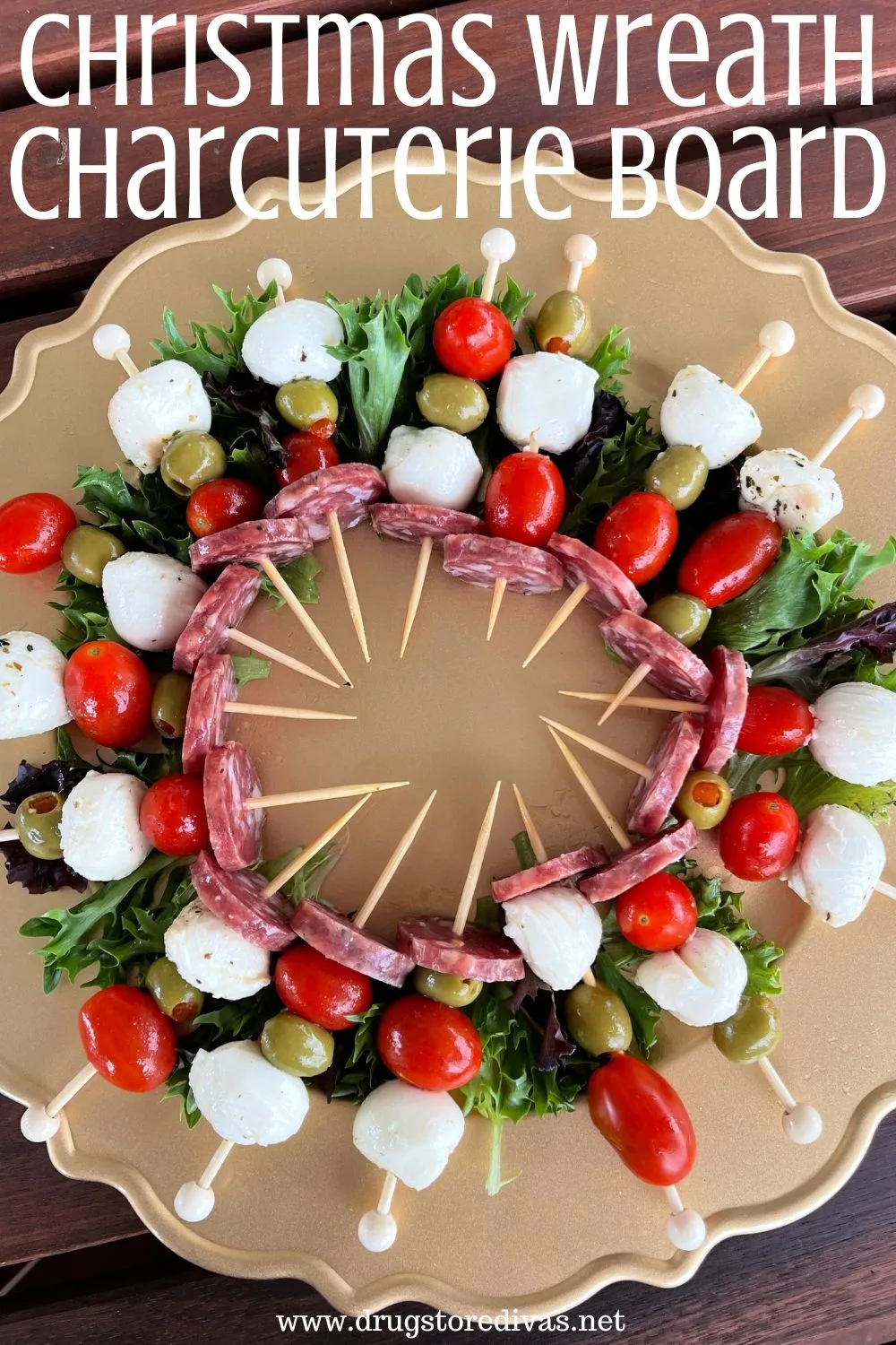 Antipasto skewers with mozzarella balls, grape tomatoes, and green olives on a gold, round tray with the words 