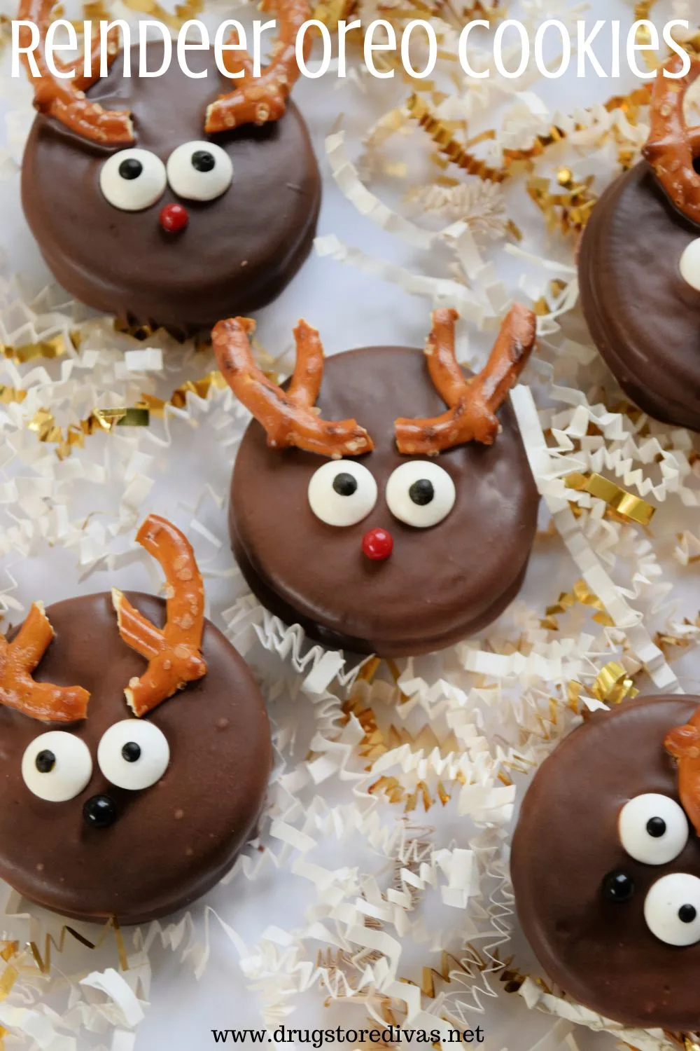 Five Oreo cookies made to look like reindeer on a white tray surrounded by white and gold paper shred with the words 