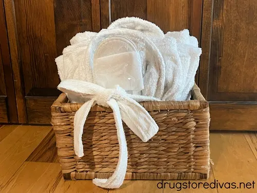 A wicker basket with white slippers and bath robes in it.