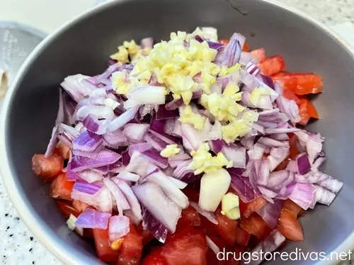 Diced tomatoes, red onion, and chopped garlic in a bowl.