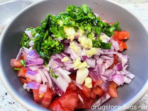 Diced tomatoes, red onion, chopped garlic, and chopped cilantro in a bowl.