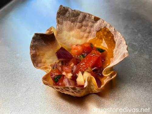 Pico de gallo in a wonton cup on a silver tray.