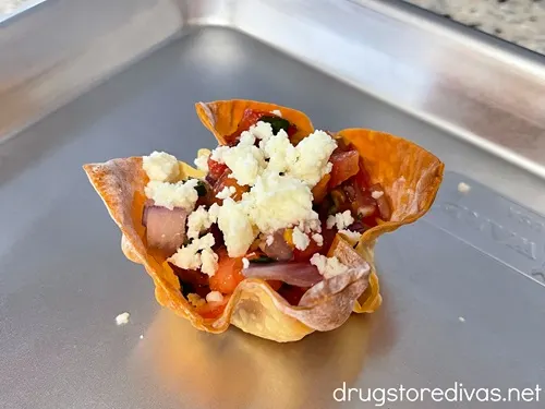 Pico de gallo and crumbled white cheese in a wonton cup on a silver tray.