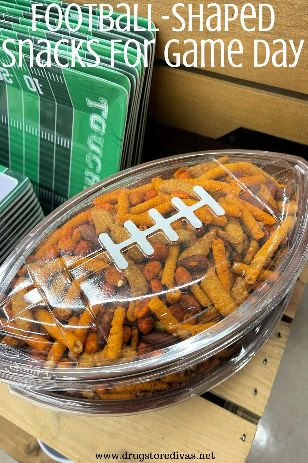 A football-shaped plastic container filled with party mix next to some plastic football field shaped plastic trays wit the words 