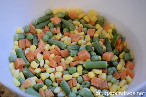 Corn, pieces of carrot, peas, and green beans in a white bowl.