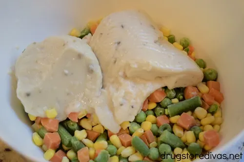 Corn, pieces of carrot, peas, and green beans, plus cream of mushroom soup, in a white bowl.