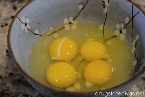 Four eggs cracked into a blue bowl.