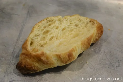 A mini croissant with the top cut off on a silver tray.