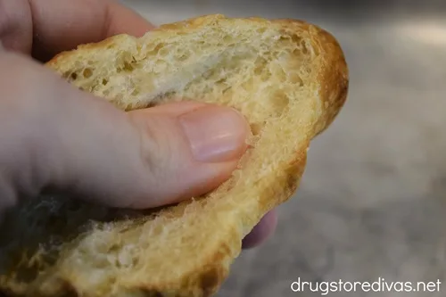 A thumb pushing down the middle of a croissant.