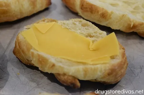 Cheddar cheese in a mini croissant that's on a silver tray.