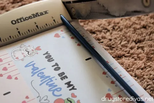 A paper trimmer cutting out Valentine's Day cards.
