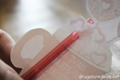 A red straw behind a cartoon cup image.