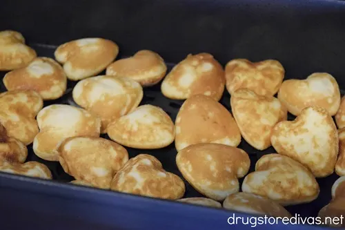 Heart-shaped mini pancakes in an air fryer basket.
