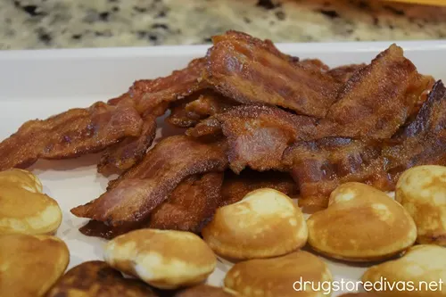 Bacon and mini heart-shaped pancakes on a white serving tray.