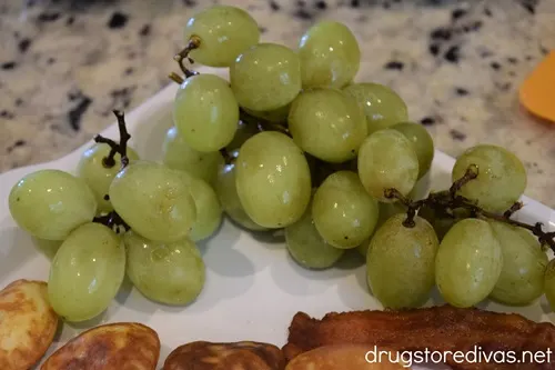 Green grapes and mini heart-shaped pancakes on a white serving tray.