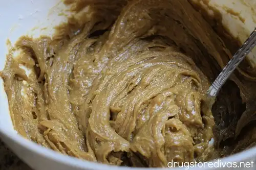 A brown cookie dough batter in a white bowl with a spoon.