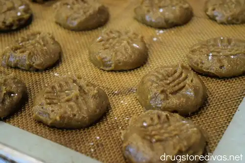 A tray of brown, raw cookies with crisscross marks on them.
