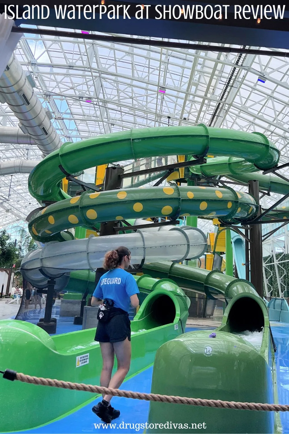 A female lifeguard standing in front of a green waterslide with the words 