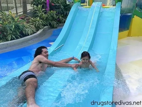 A teenaged boy helping a toddler down a small waterslide at Island Waterpark at Showboat Hotel.