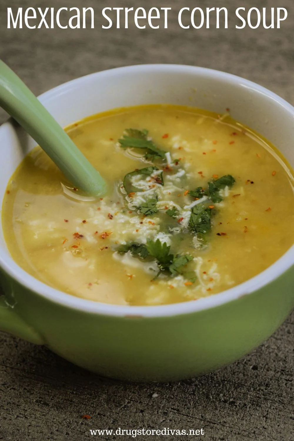 A dark yellow soup with cilantro and white cheese on top in a green bowl with a green spoon in it and the words 