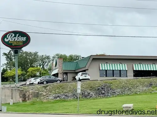 The outside of a Perkins restaurant with a few cars parked outside.
