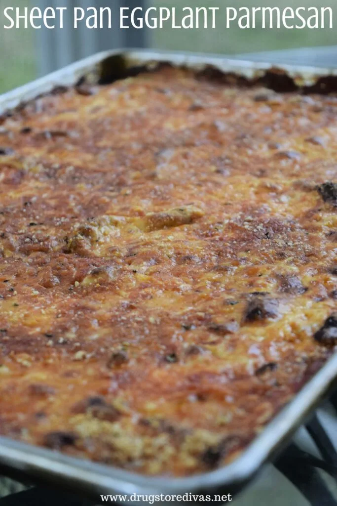 A silver rimmed sheet pan filled with eggplant parmesan on a table with the words "Sheet Pan Eggplant Parmesan" digitally written on top.