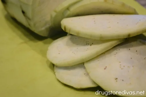Sliced eggplant rounds a yellow green cutting board.